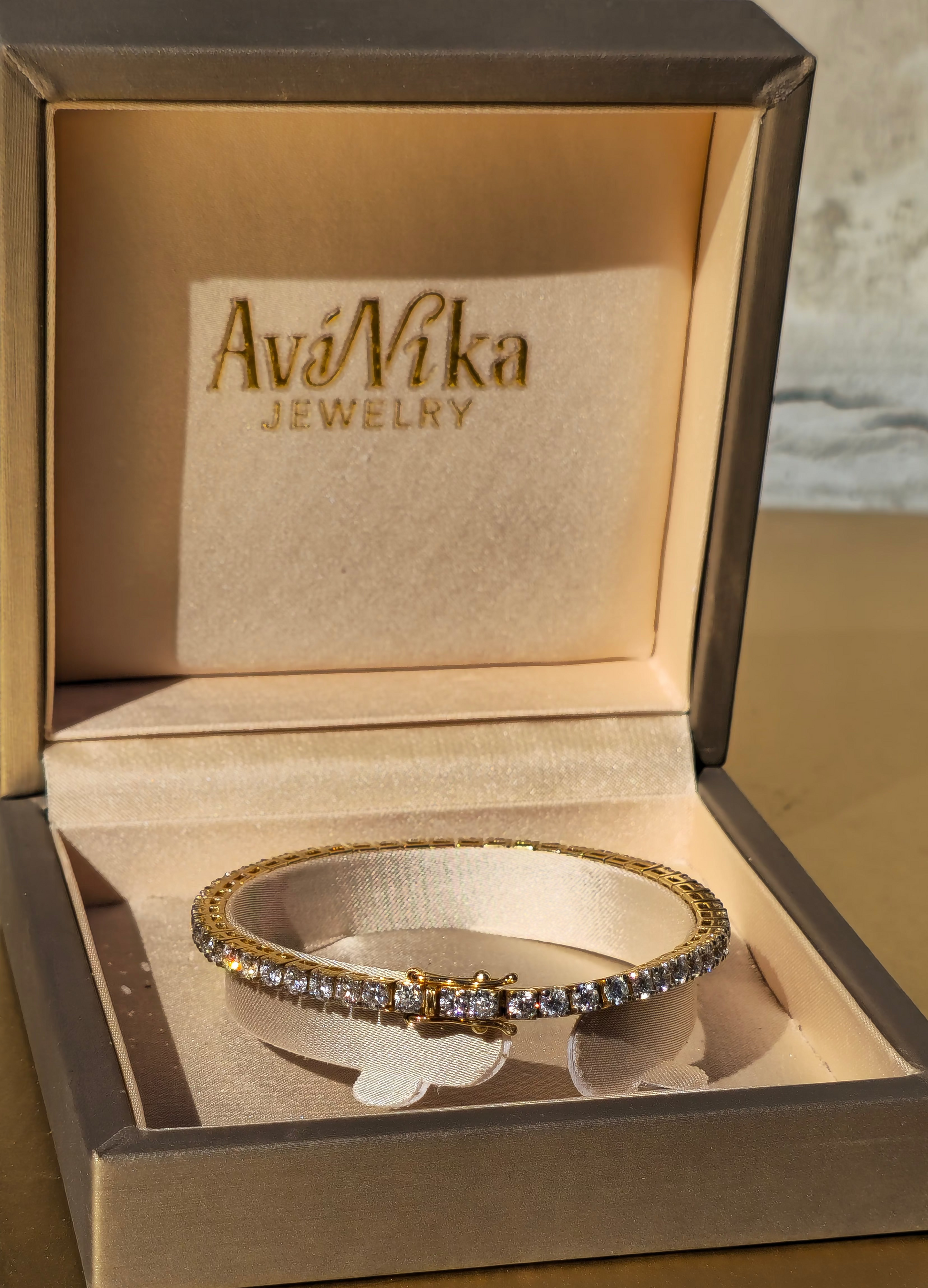 Gold tennis bracelet with lab diamonds in a jewelry box labeled 'AviNika Jewelry'.