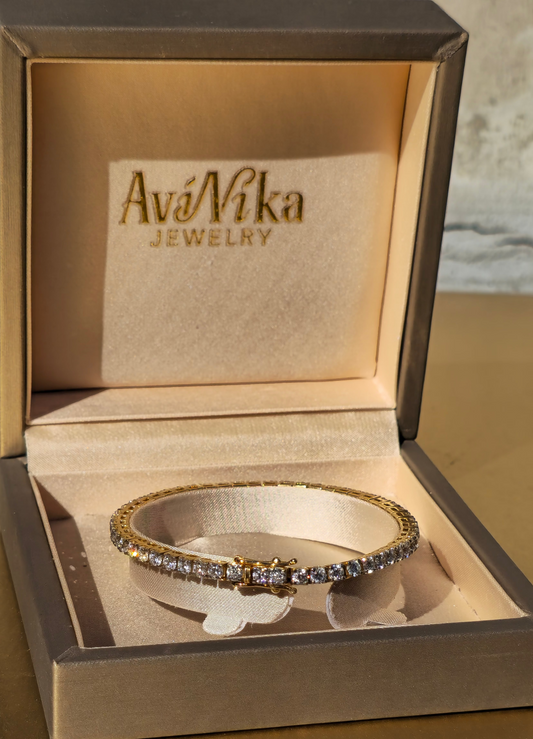 Gold tennis bracelet with lab diamonds in a jewelry box labeled 'AviNika Jewelry'.