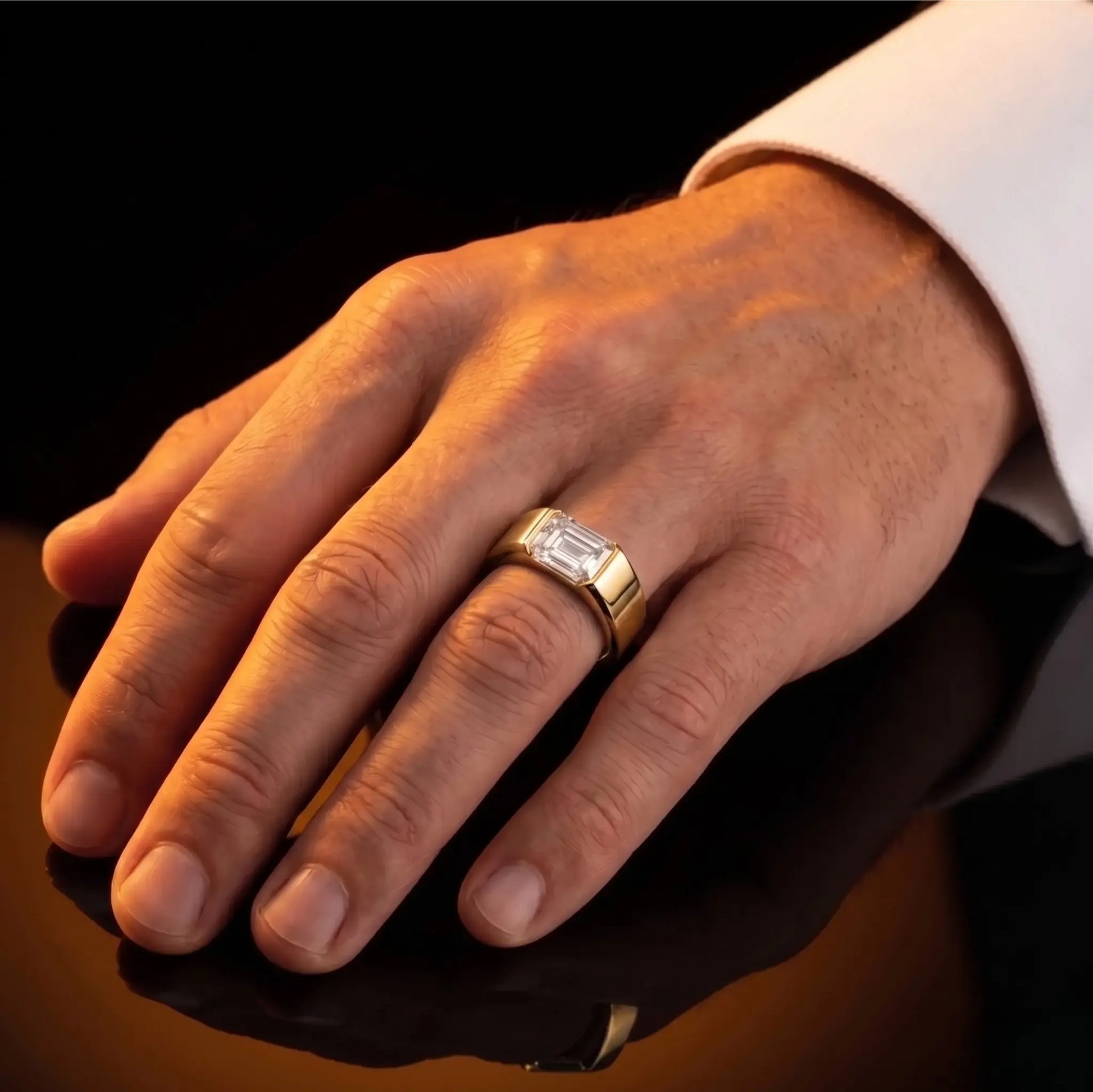 Hand wearing a gold ring with a diamond on a dark background